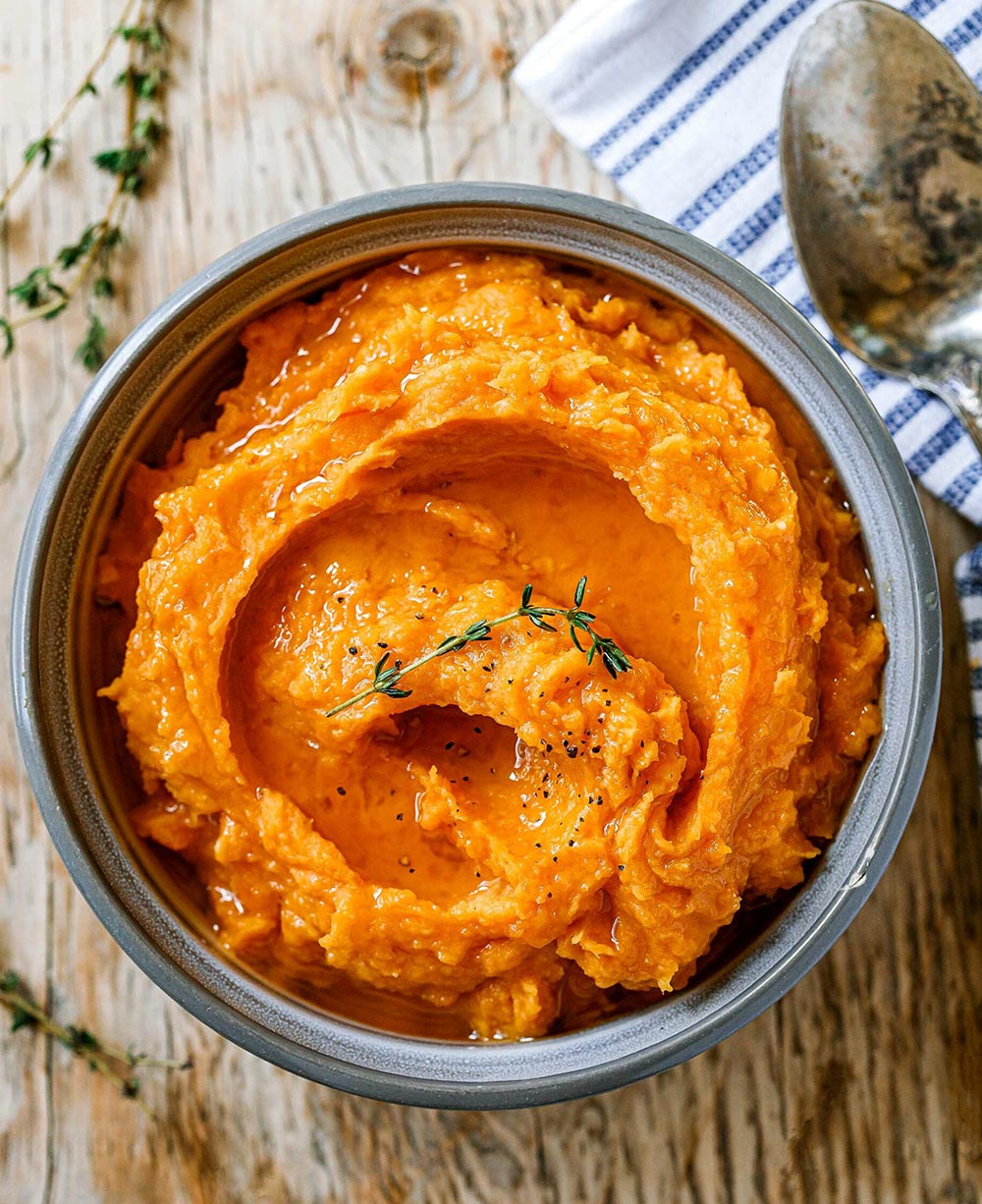An overhead view of mashed sweet potato in a bowl. 