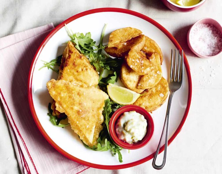 Battered plant-based fillets served with potato wedges, rocket, a lemon wedge, and tartare sauce—a delicious addition to your tofu recipes.