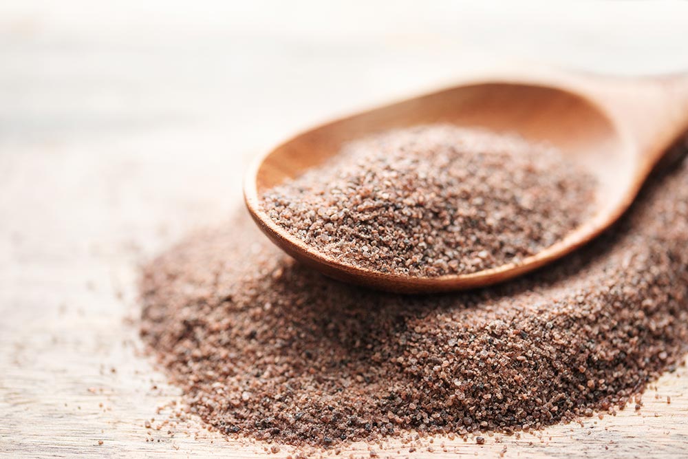 A spoon sits atop a mound of black salt.