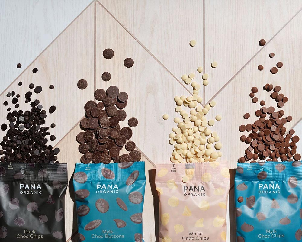 Four bags of different Pana baking chips are opened and spilling out onto a patterned benchtop.