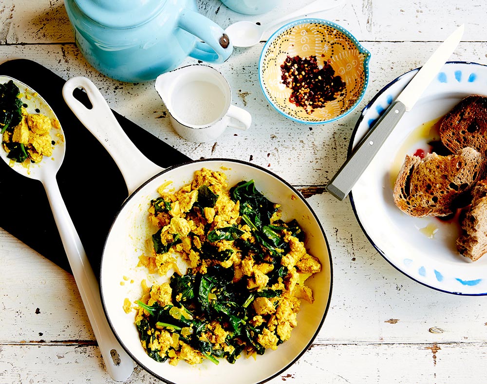 Overhead view of a frying pan filled with a spinach and tofu scramble.