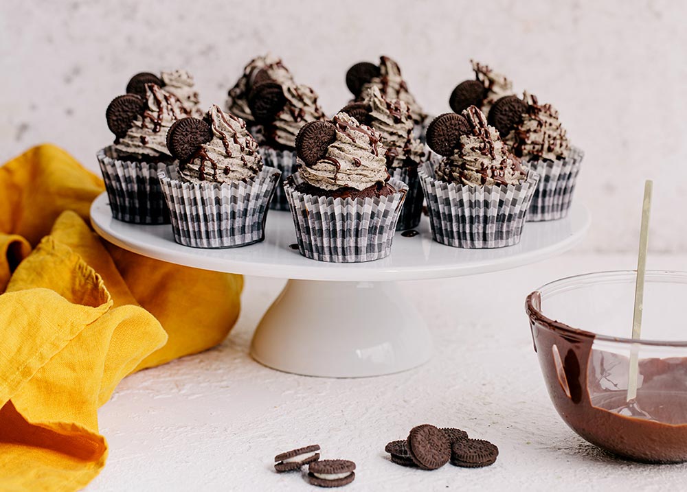 A cake stand holds a beautifully decorated Oreo cupcakes. 