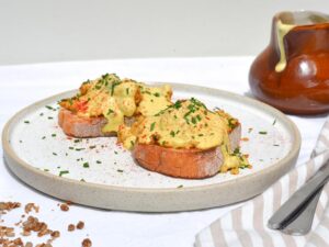 Vegan eggs benedict served on toast on a white dish.