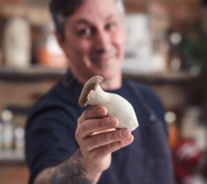 Chef Derek Sarno holds a mushroom to camera.