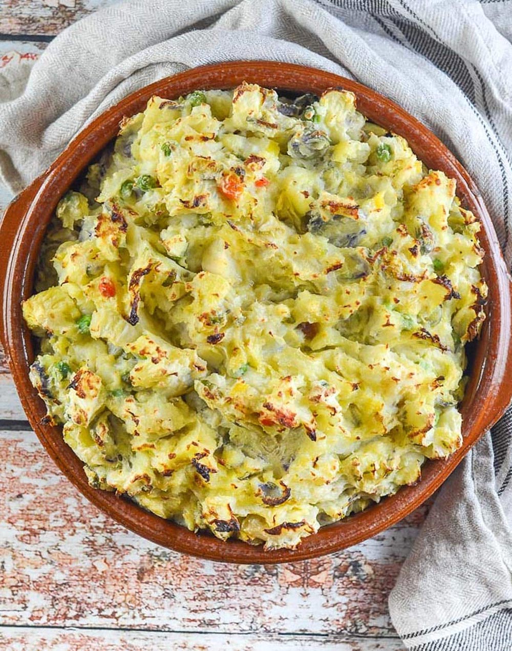 A casserole dish full of bubble 'n squeak sits on a bench.