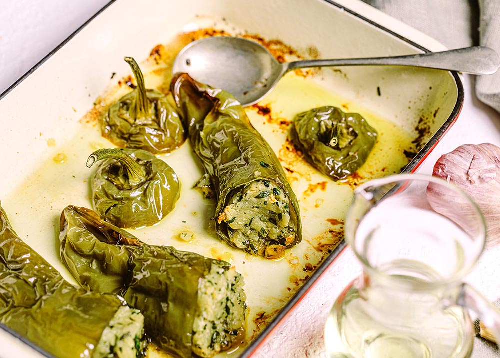 Stuffed green capsicums sit in an oven tray.