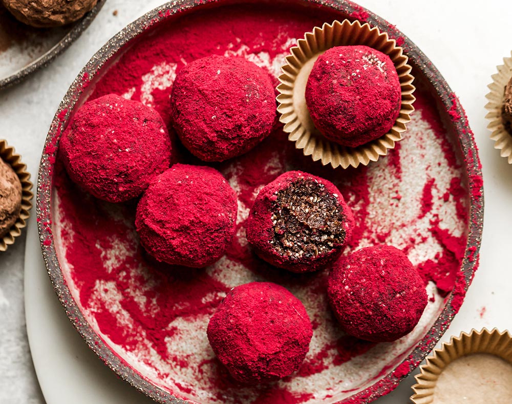 Chocolate truffles on a plate covered in a bright beetroot powder dusting.