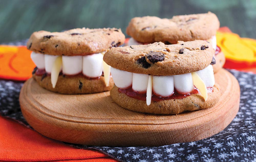 Chocolate chip cookioe sandwiches decorated with marshmallows and almonds are fashioned into sets of vampire teeth.