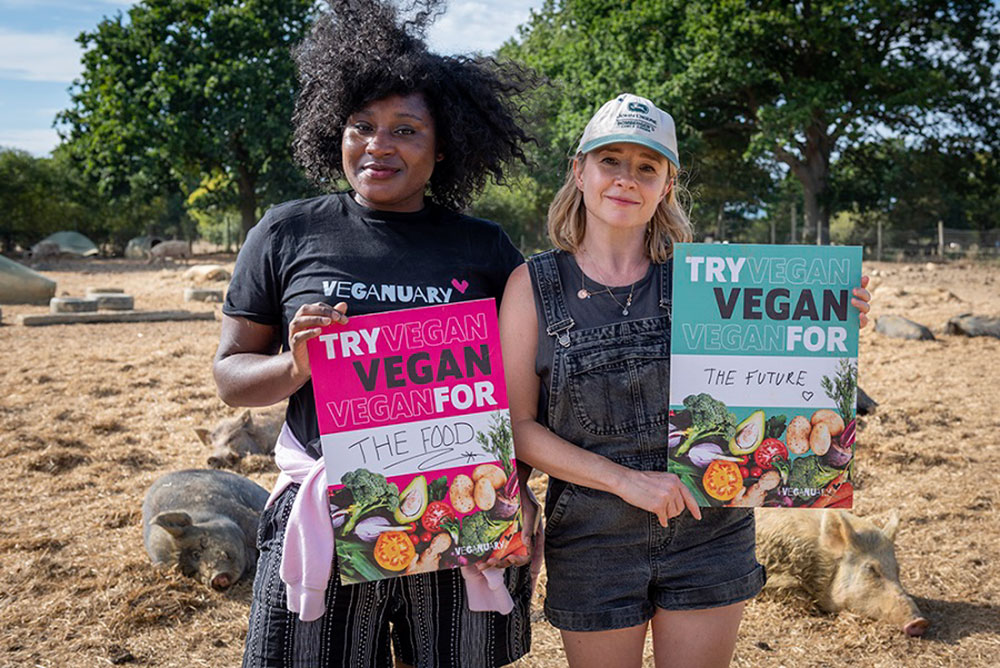 Two women at a farm sanctuary holding up Veganuary signs.