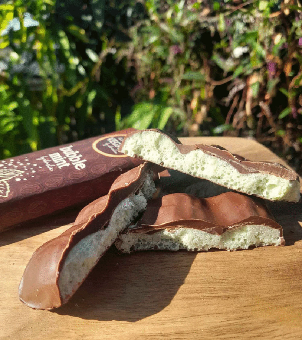 A block of bubble mint chocolate has been broken up into pieces on a board, showing it's Aero-like structure.