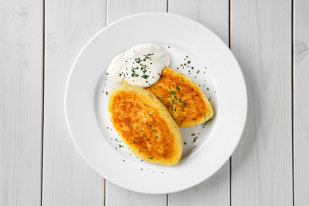 Overhead view of potato patties with sour cream.