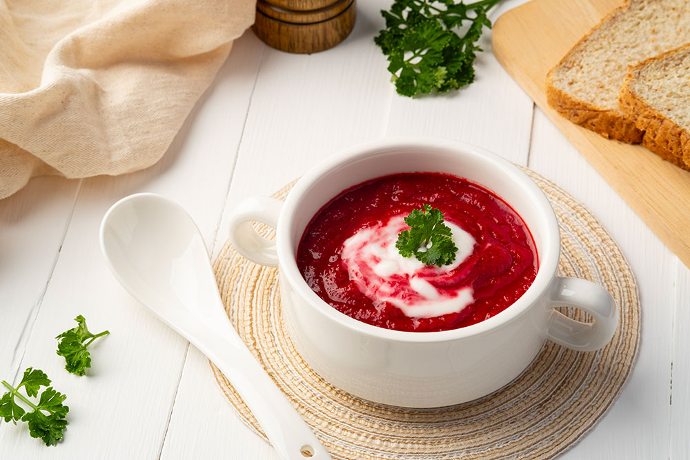 Beetroot soup with cream in a white bowl.