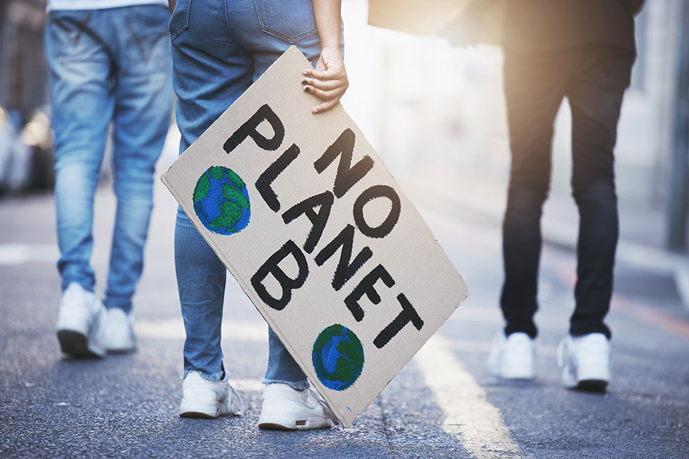 A person with climate change banner protests on asphalt road in the city.