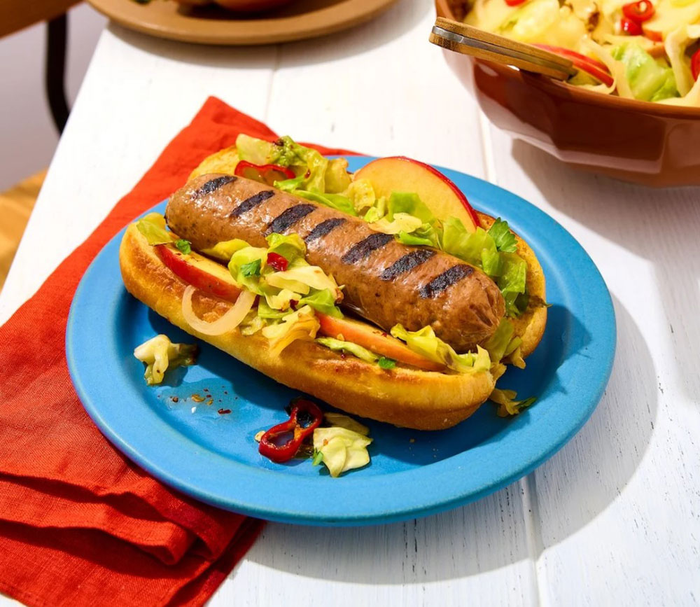 A vegan hot dog with the lot on a blue plate. 