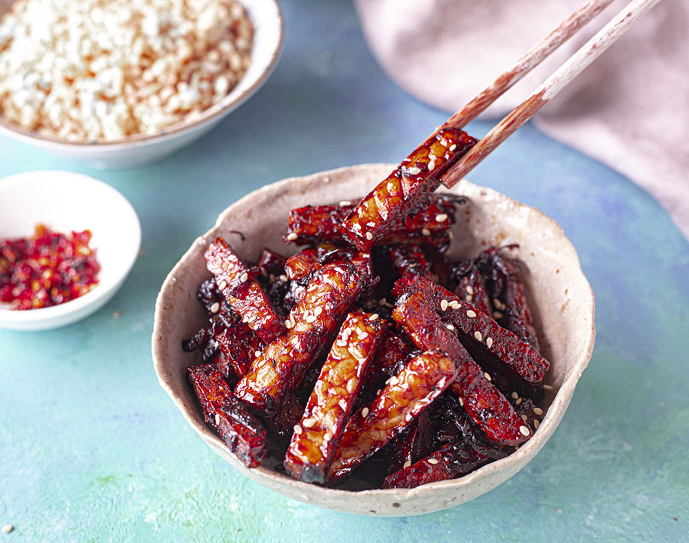 A bowl of Tempeh Goreng topped with sesame seeds.