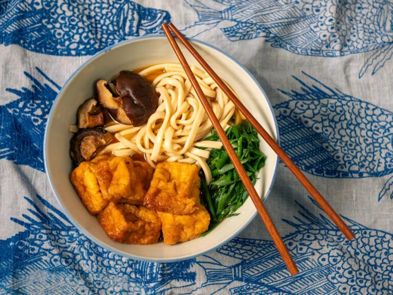 A bowl of tofu udon soup with chopsticks.