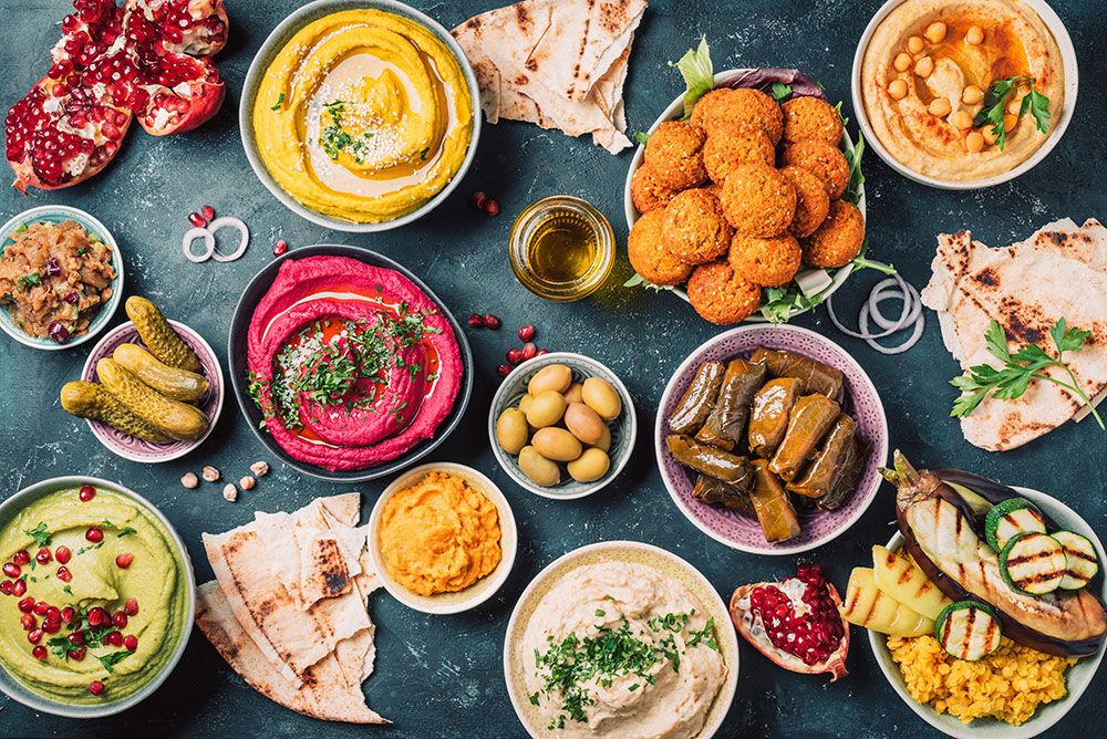 An overhead shot of a large spread of vegan food, with dips, pickles, dolmades and more.