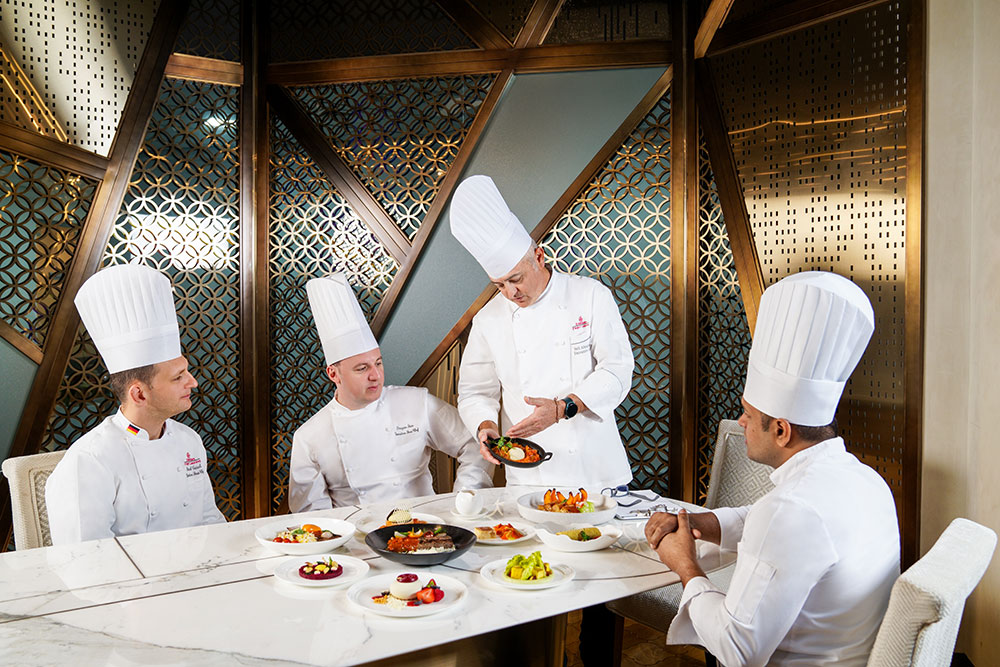 Four of Emirates chefs surround a dining table with their latest vegan dishes in front of them.