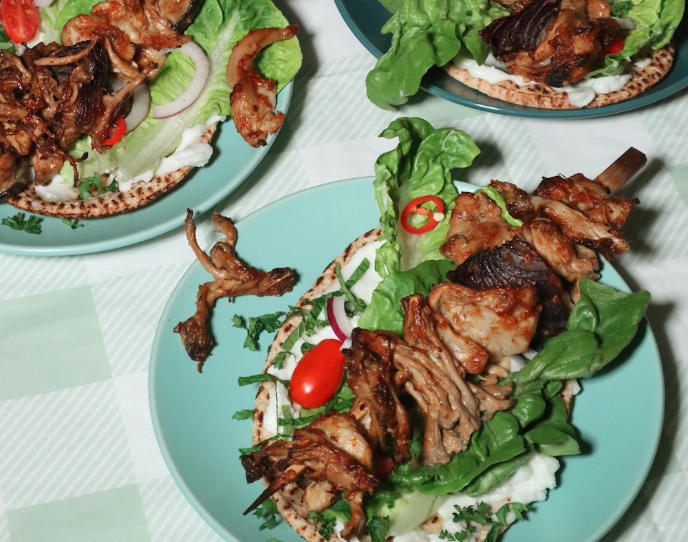 Vegan BBQ recipe ideas - Plant-based 'lamb' shish kebabs on served on green plates at a table setting.