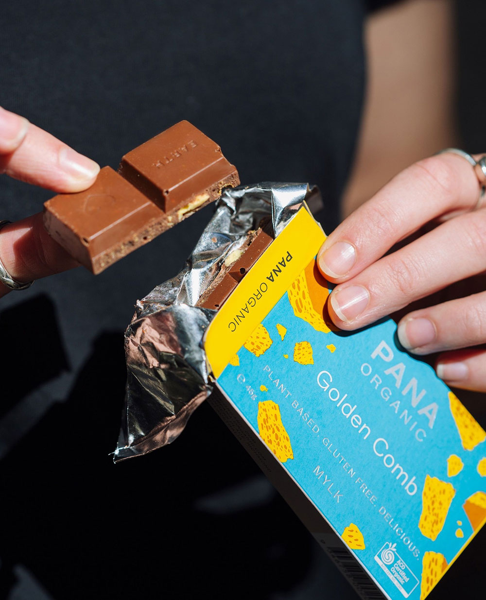 Hands are holding a block of Pana Golden Comb, with two squares broken off to eat.