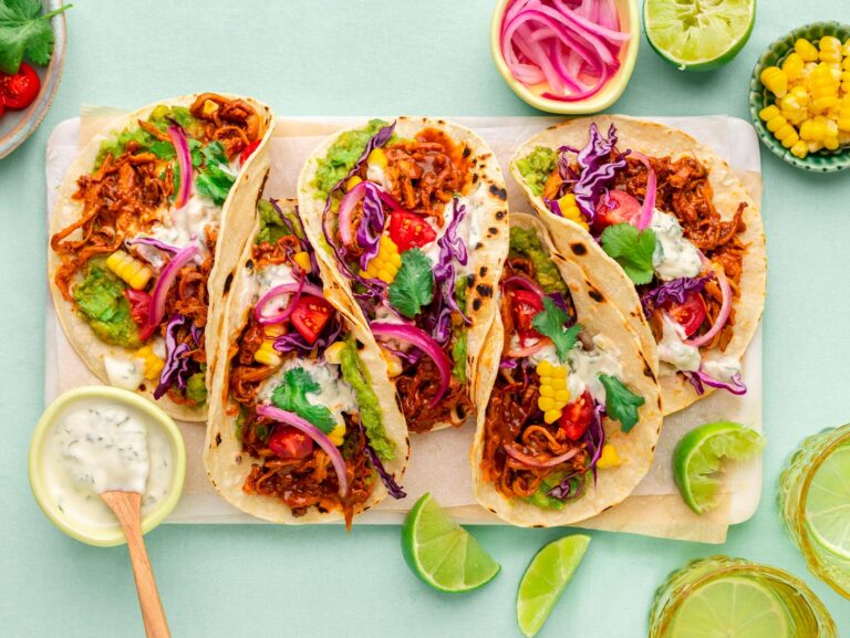 Overhead view of pulled mushroom tacos on a mint green background.