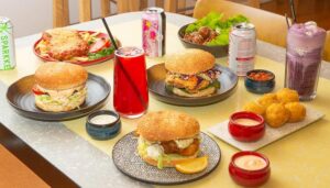 A classic diner-style spread of burgers, parmas and sides, with condiments and sodas