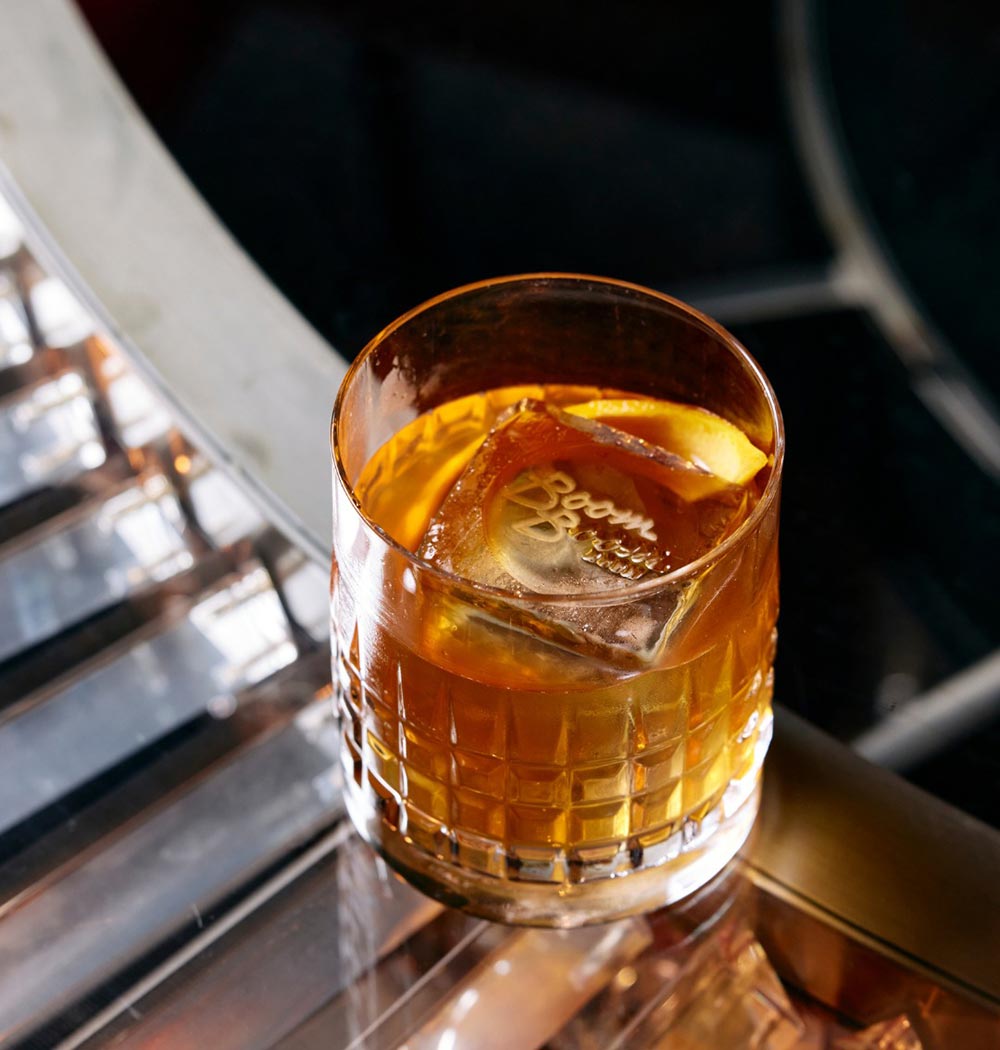 A glass of Japanese whisky with a giant ice cube with the imprint of the bar, The Boom Boom Room. 