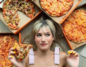 vegan youtube channels: Candace from Edgy Veg lies on the floor looking up, surrounded by vegan pizzas.