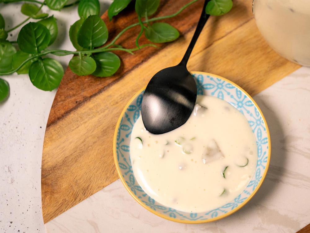 An overhead image of homemade aquafaba mayo with pickles and capers.