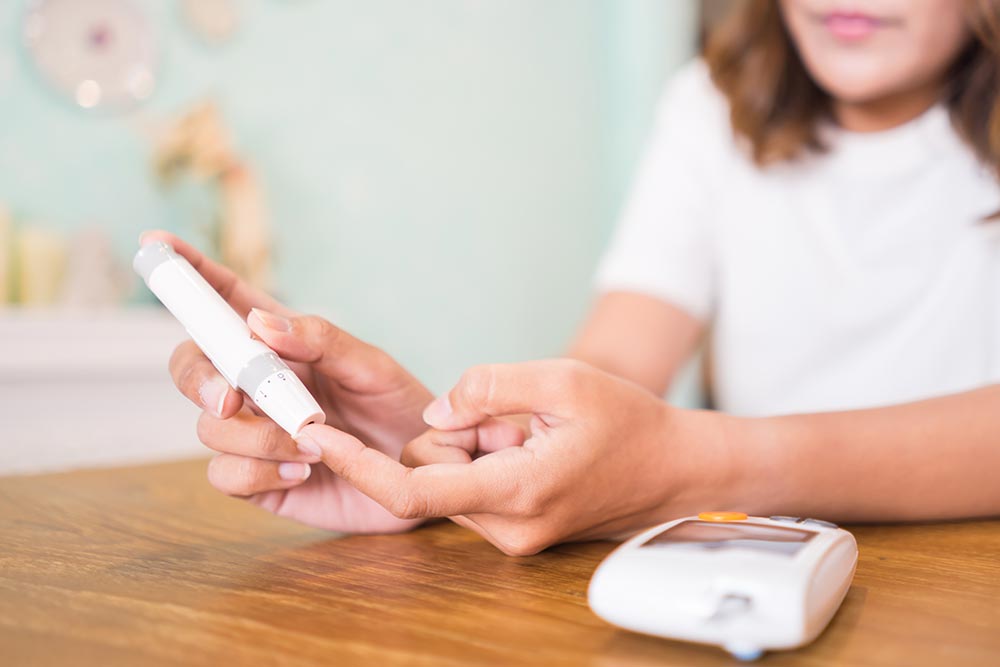 Plant-based diet shown to boost longevity for people with diabetes: Close up of hands using lancet on finger to check blood sugar level by glucose meter
