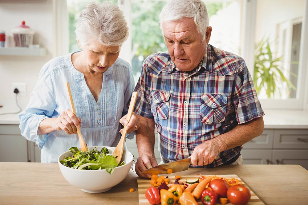 Plant-based diet shown to boost longevity: Senior couple preparing a salad together in the kitchen.
