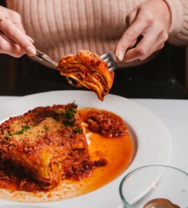 A woman cuts into a slice of delicious looking lasagne at Fungi e Tartufo.