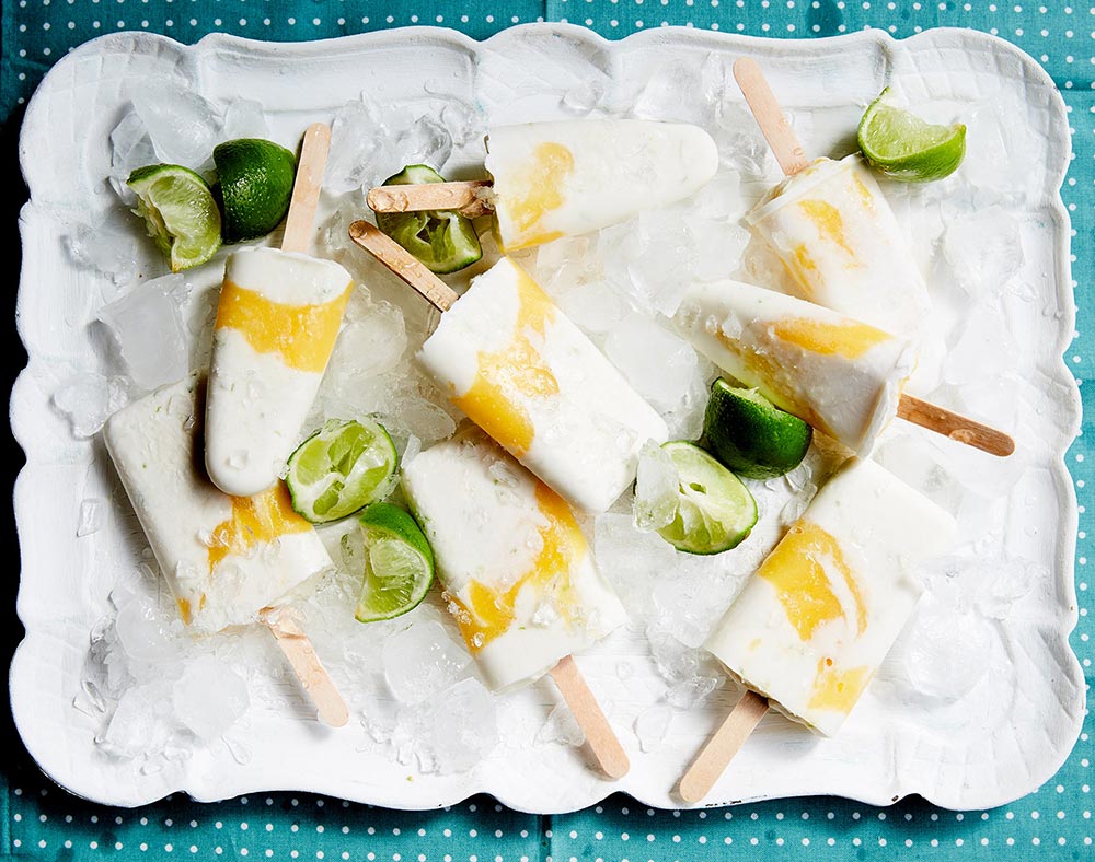 A tray of mango, lime and coconut popsicles on a tray of ice. 