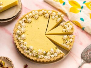 An overhead shot of a beautifully decorated lemon tart, with three slices pre-cut.
