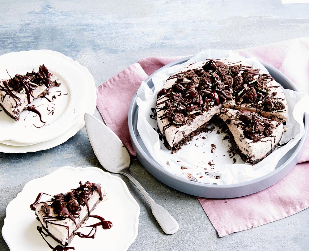 Vegan desserts: A cookies and cream ice cream cake on a white serving plate. Two smaller dessert plates hold individual slices. 