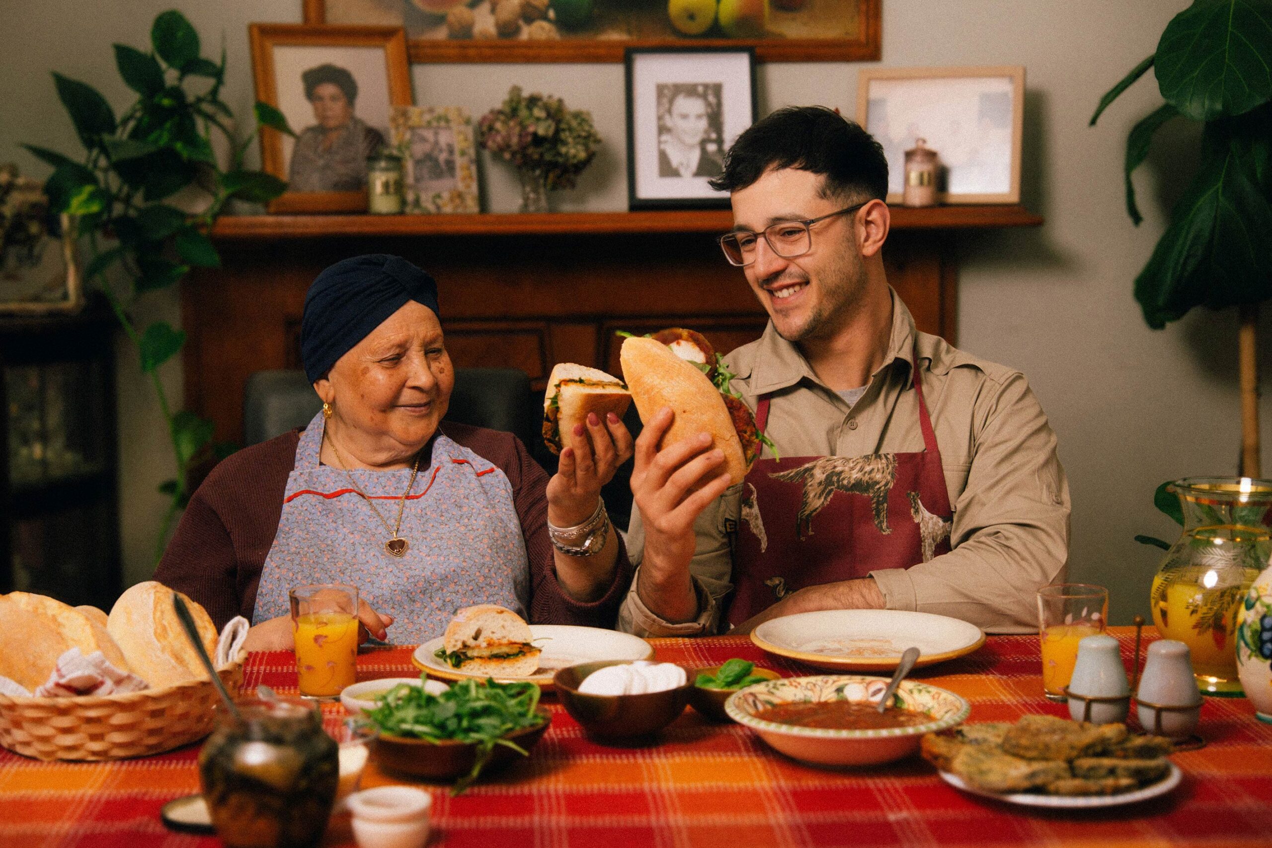 Nanna sitting at her dining table with her grandson Josh holding freshly made eggplant paninis.