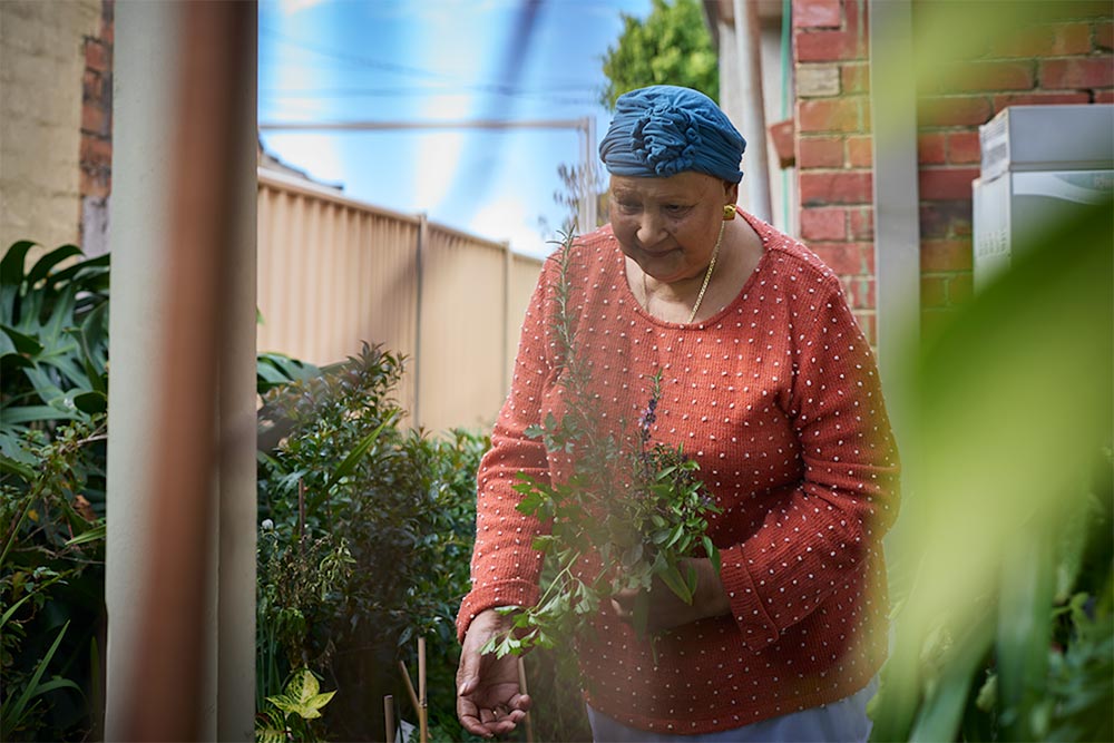Mirella collects herbs from the garden outside.