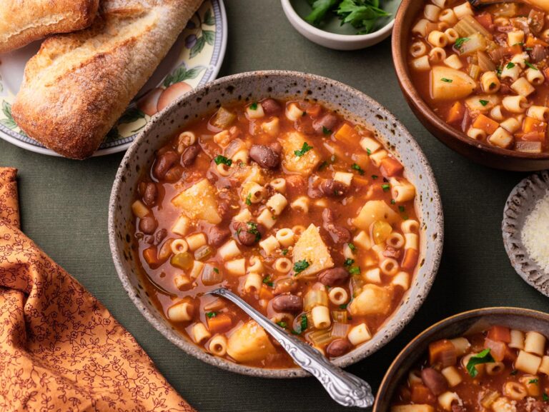 A bowl of pasta fagioli with crusty bread to the side.