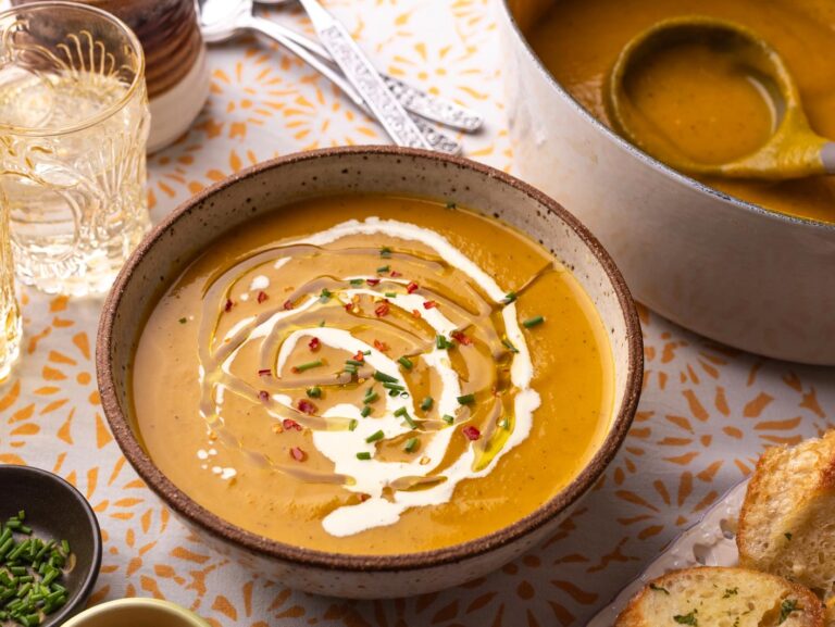A bowl of creamy pumpkin soup topped with chopped parsley