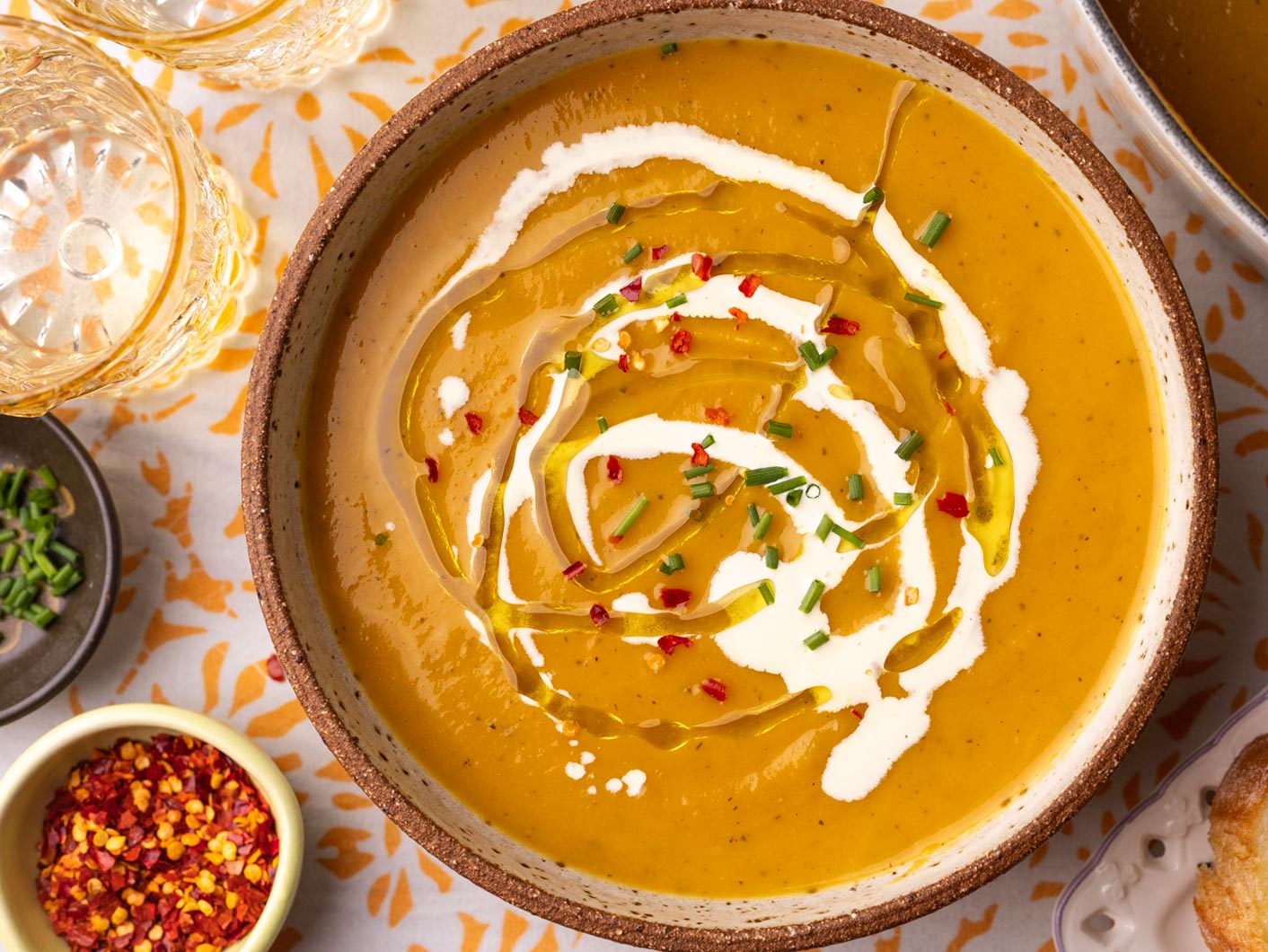A bowl of creamy pumpkin soup topped with chopped parsley