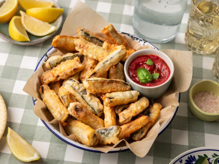 Battered zucchini chips served in a bowl with a side of Napoli sauce