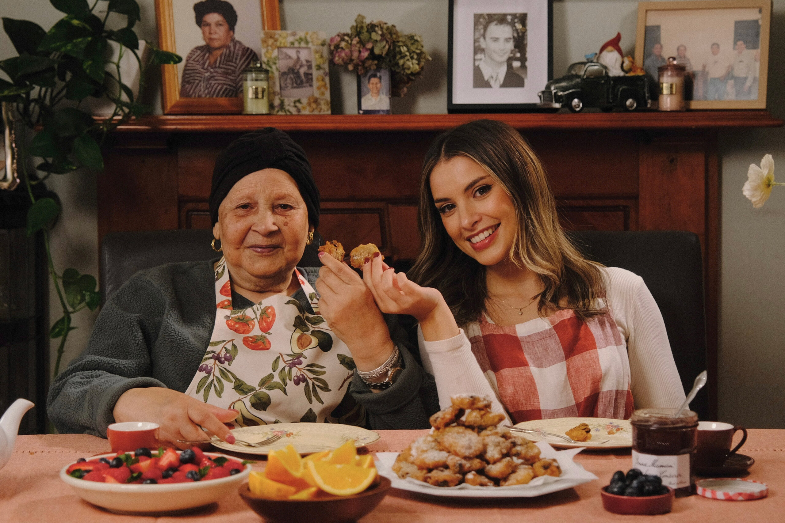 Nanna sitting at her dining table with her granddaughter Claud with a plate of fresh frittole in front of them.