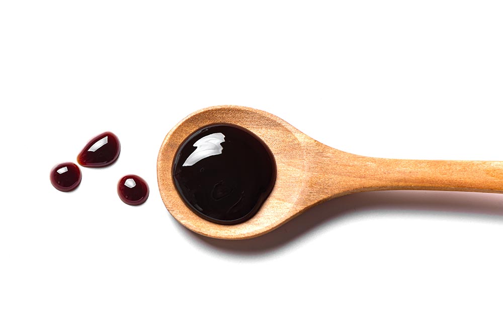 Overhead shot of vegan fysh sauce on a wooden spoon. 