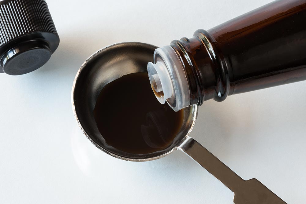 Overhead view of liquid smoke pouring into a measuring spoon - secret weapon’ vegan seasonings