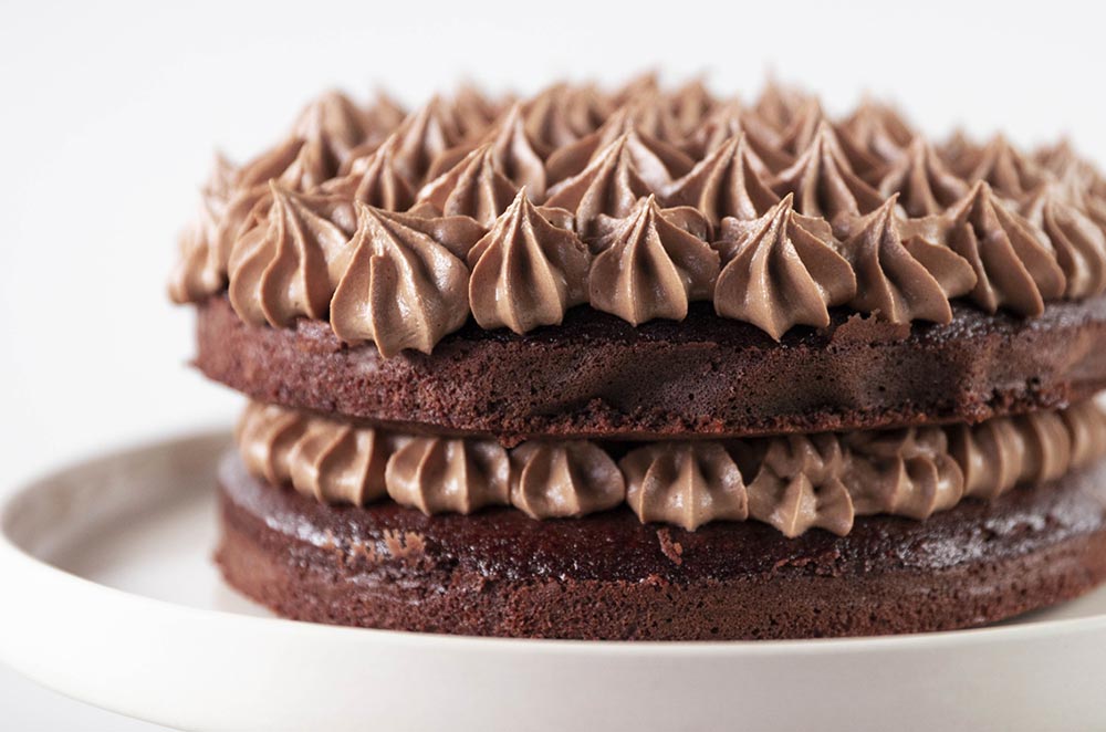 A two-tiered chocolate celebration cake, expertly piped with chocolate frosting. 