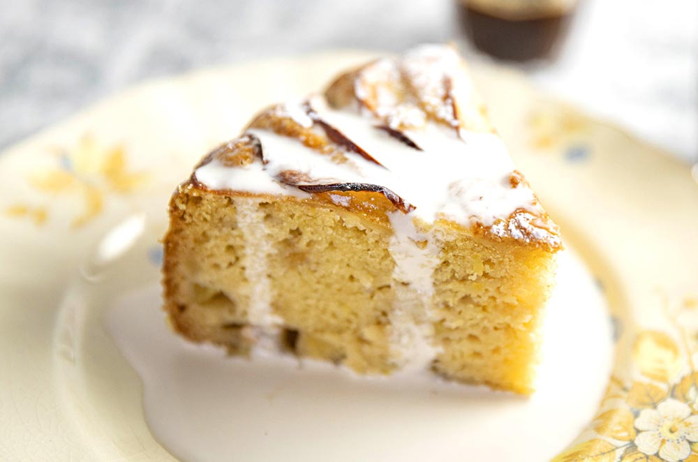 A slice of apple and lemon cake served with cream. 