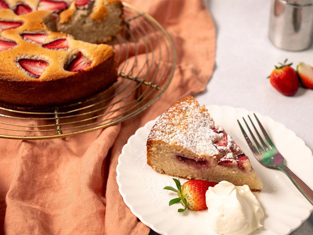 A slice of strawberry tea cake, served with a side of whipped cream. 