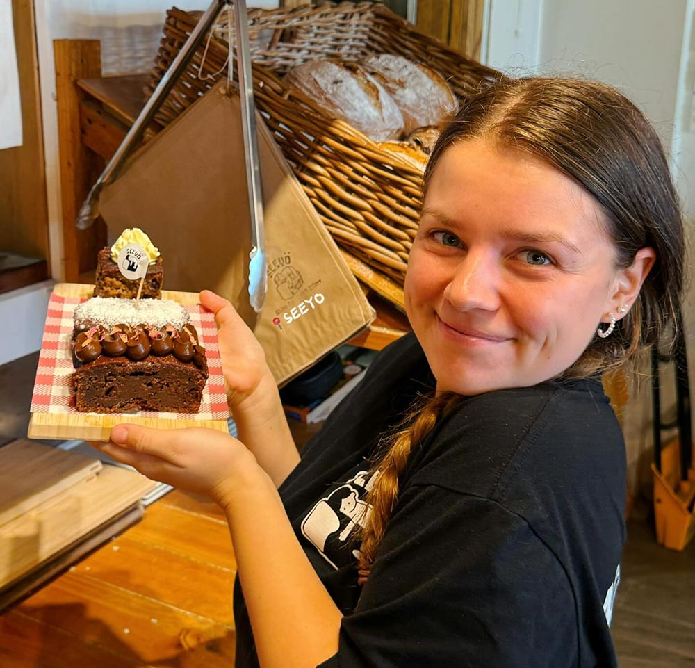 An employee holds up a tray with various cakes from See Yo Cafe and Bakery