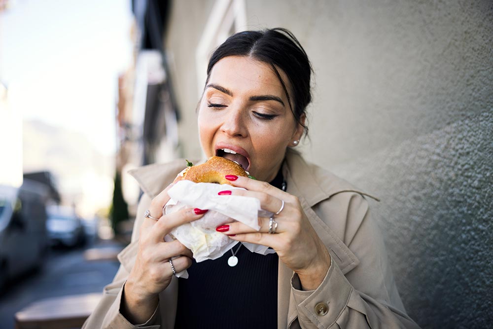 A woman enjoys a bagel outside – study shows vegan diet leads to weight loss (even with processed foods) 
