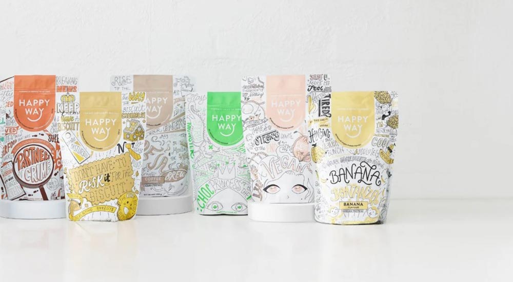 The vegan range of protein powders from Happy Way stand upright on a white bench. 